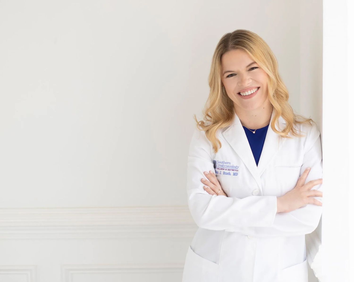 Smiling doctor in white coat against neutral background.