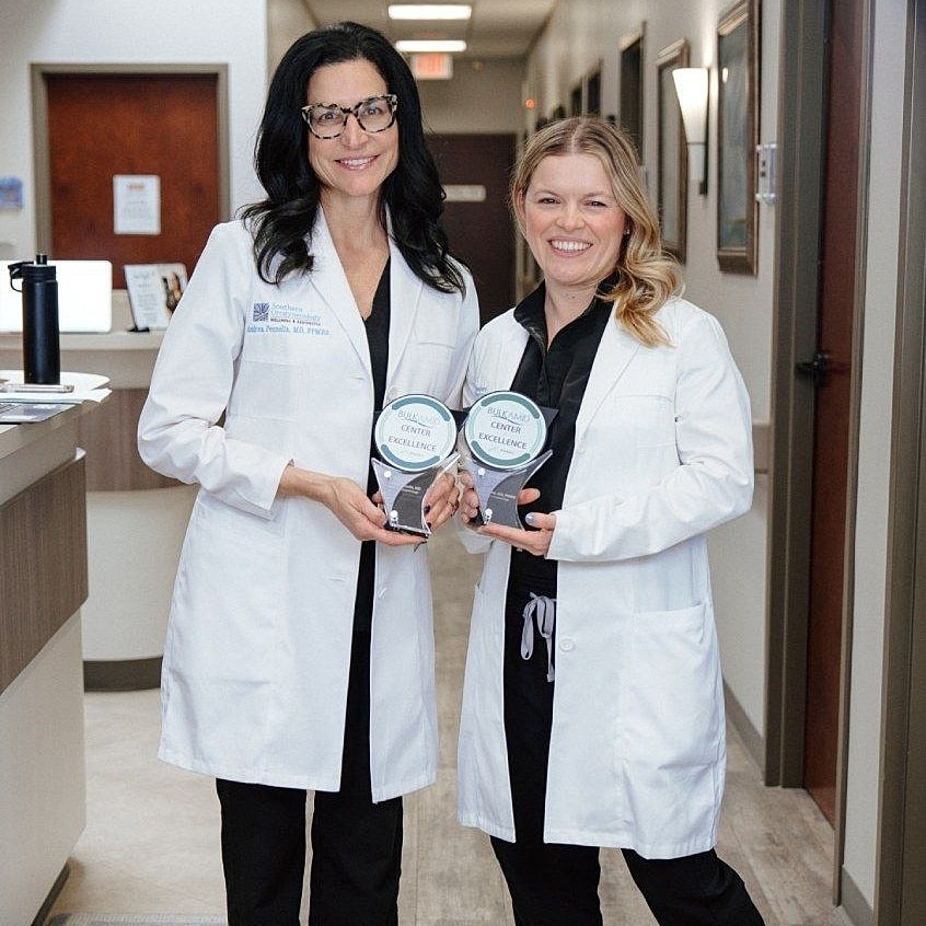 Two healthcare professionals holding awards.